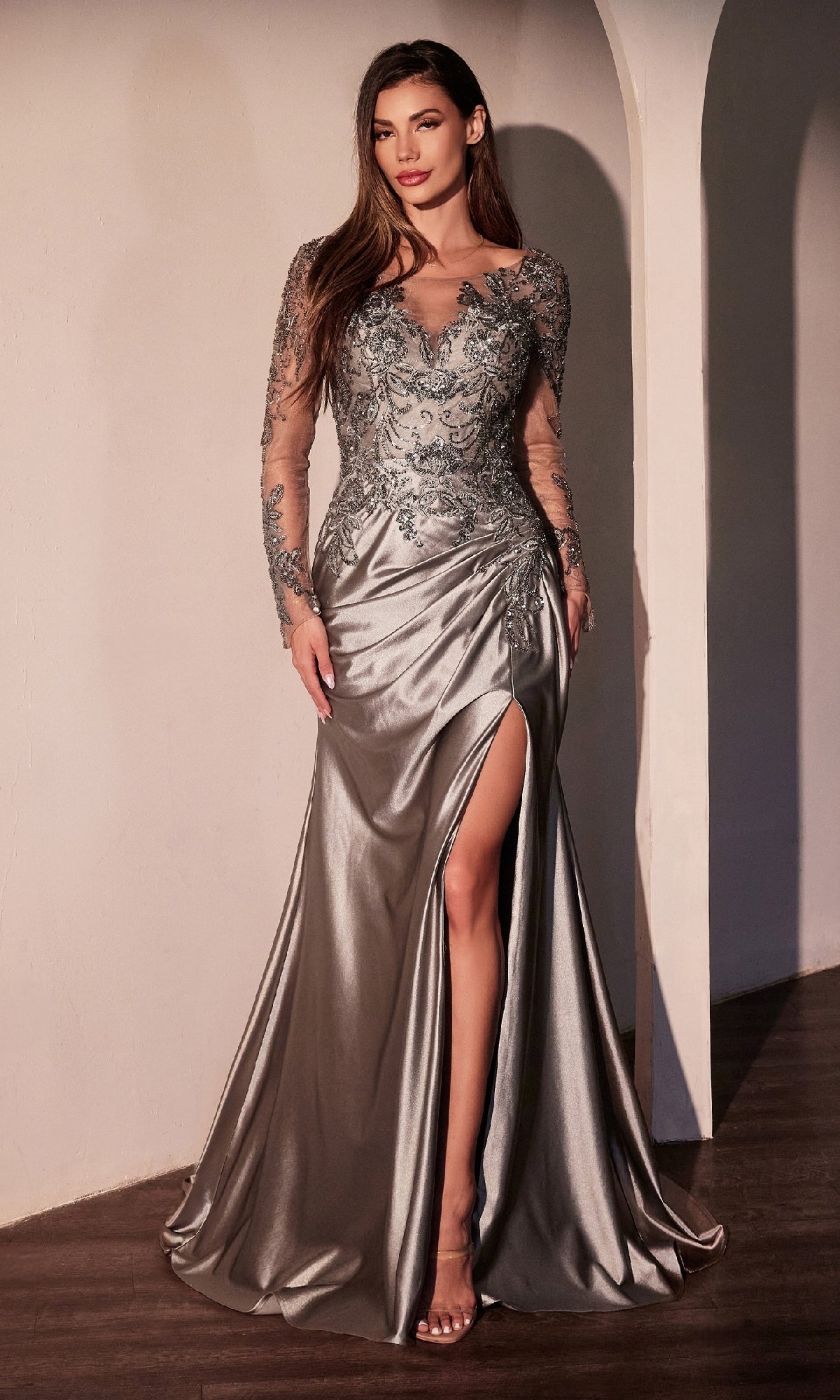 A woman stands indoors against a white wall, wearing the Ladivine CDS505—a long sleeve lavender formal dress—an elegant option that rivals any prom dress.